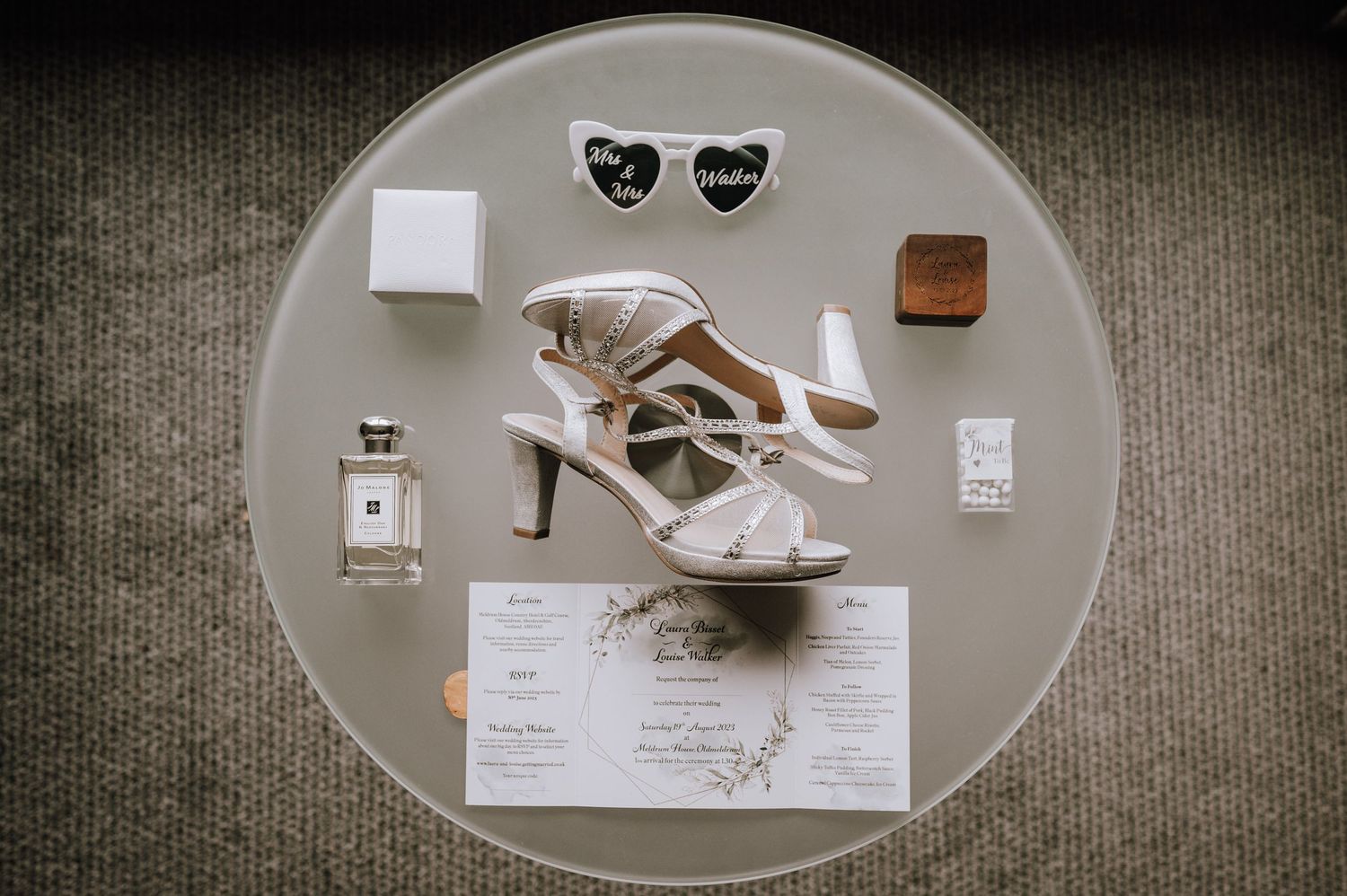 Wedding details including shoes and papers arranged on a round table. Meldrum House Wedding Photography.