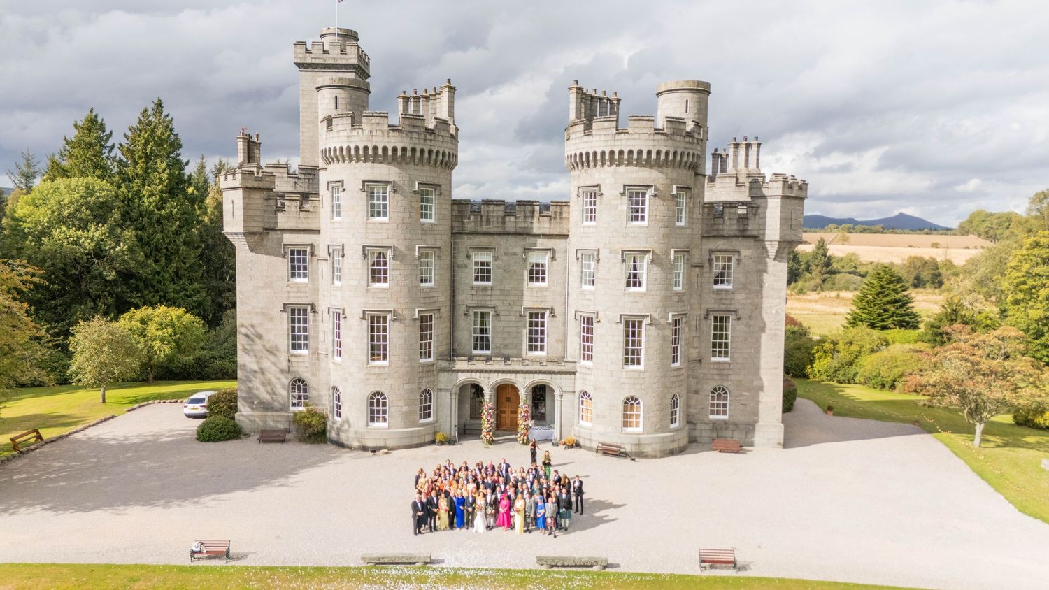 Stunning Scottish castle wedding venue with gathered guests on sunny day.