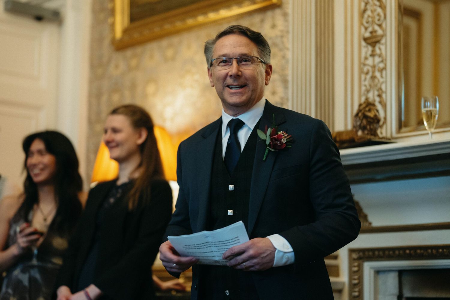 Drumtochty Castle  Wedding Photography. A speaker holds papers while presenting at an elegant indoor venue.