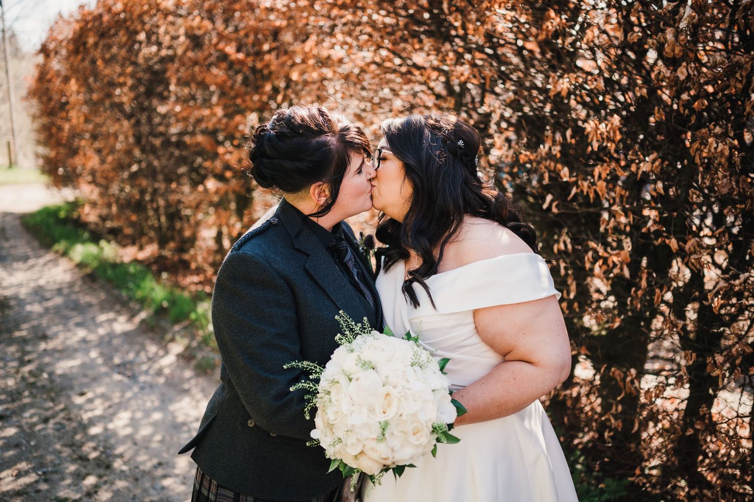 Logie House Wedding Photography. A romantic wedding moment captured on a garden path with autumn foliage in the background.