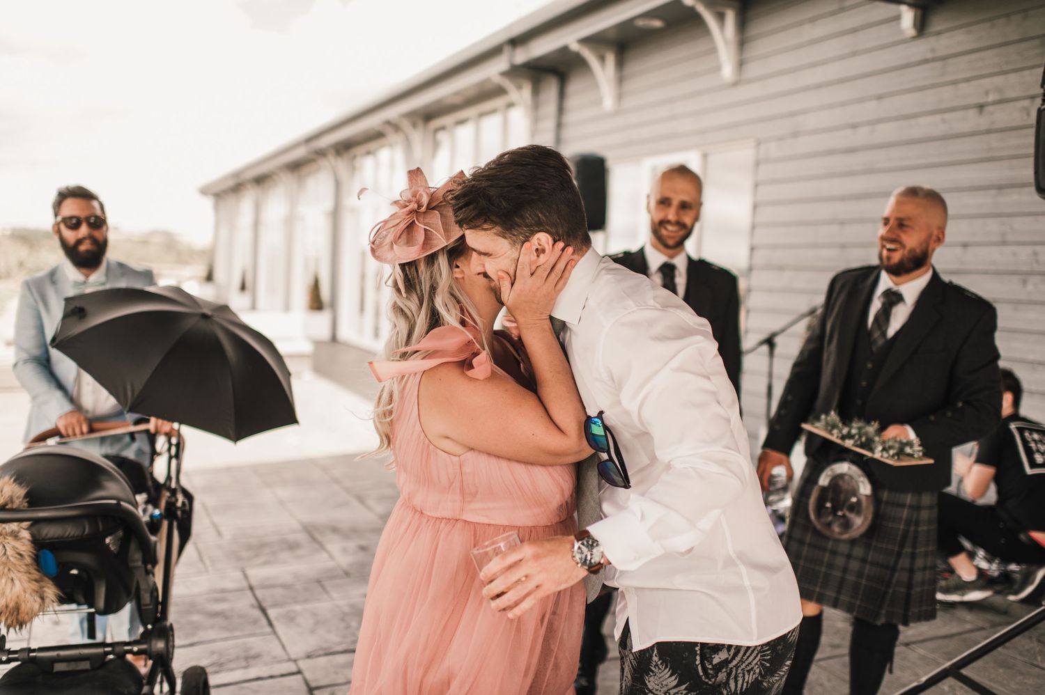 Emotional moment captured at wedding celebration with guests in traditional Scottish attire.