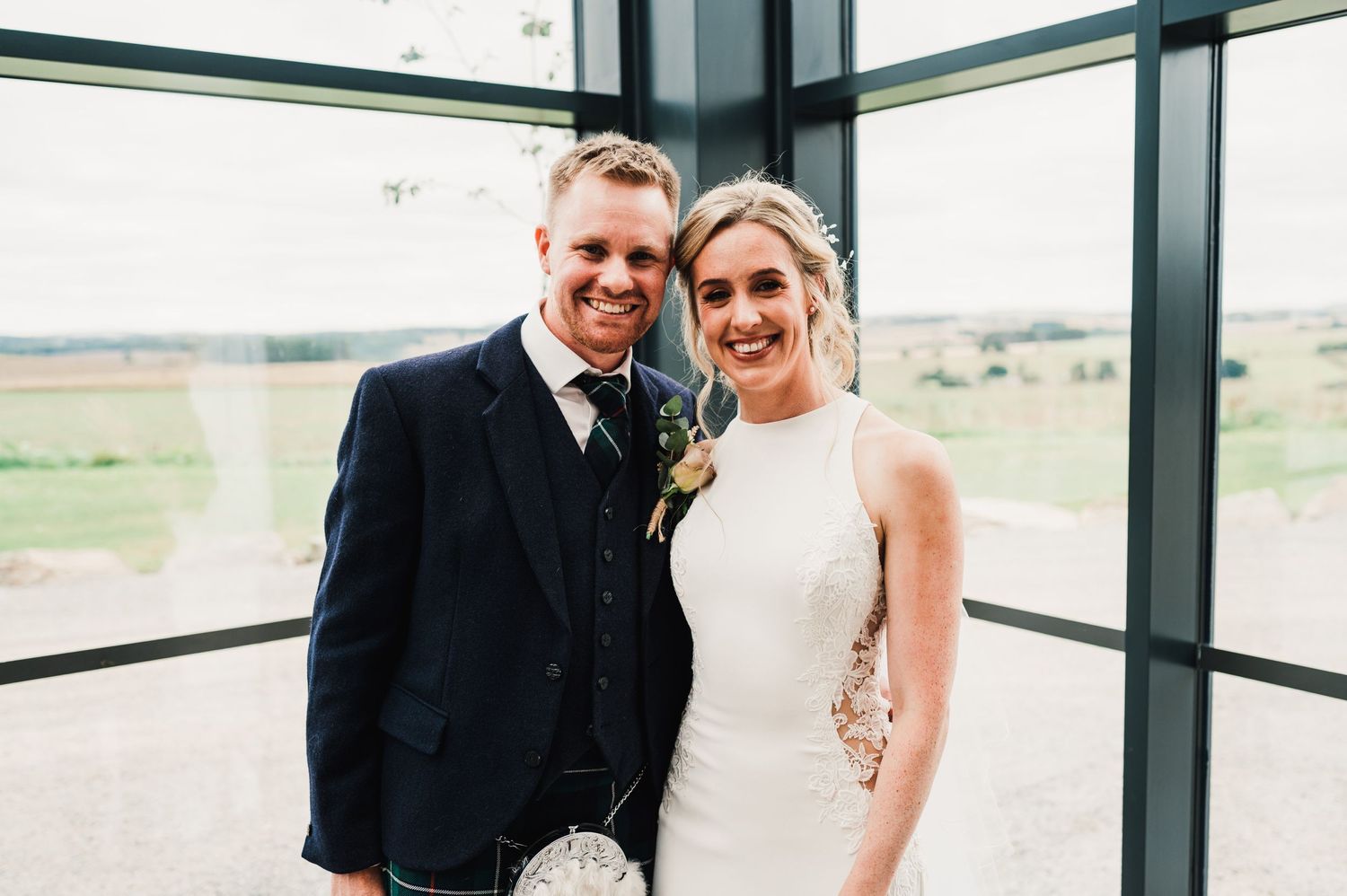 Wedding portrait in modern glass-walled venue with countryside views.