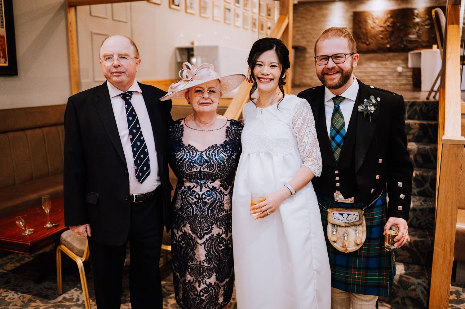A formal wedding portrait features traditional attire including a kilt and white lace dress.