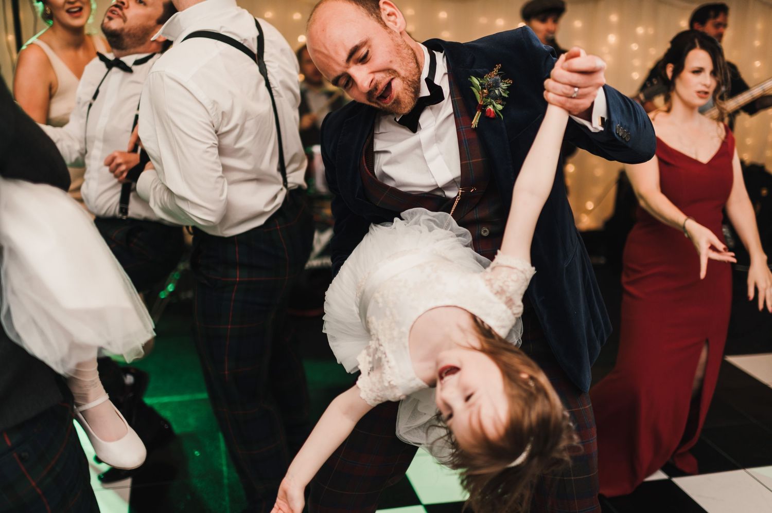 Dramatic dance move during wedding reception shows guests enjoying lively celebration on the dance floor.