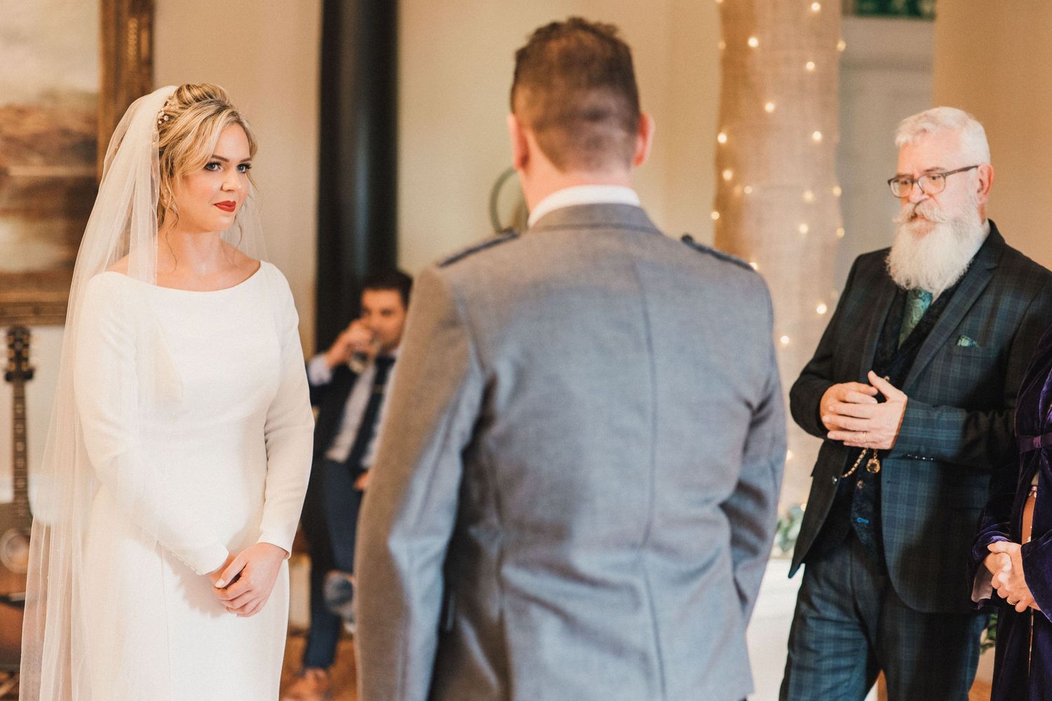 Indoor wedding ceremony scene with elegant decor and string lights creating romantic atmosphere.