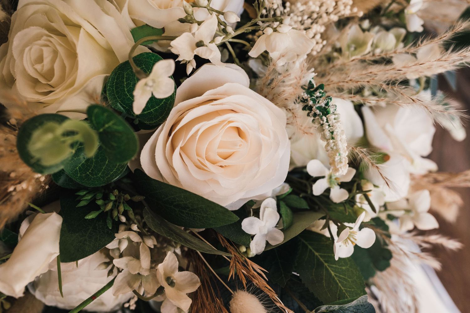 Close-up of cream roses and delicate white flowers in romantic wedding bouquet arrangement.