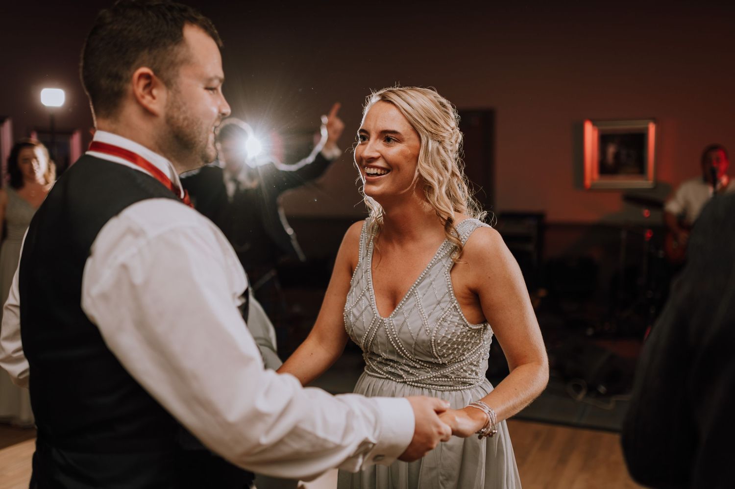 A couple shares a romantic dance moment at their wedding reception in a dimly lit venue.