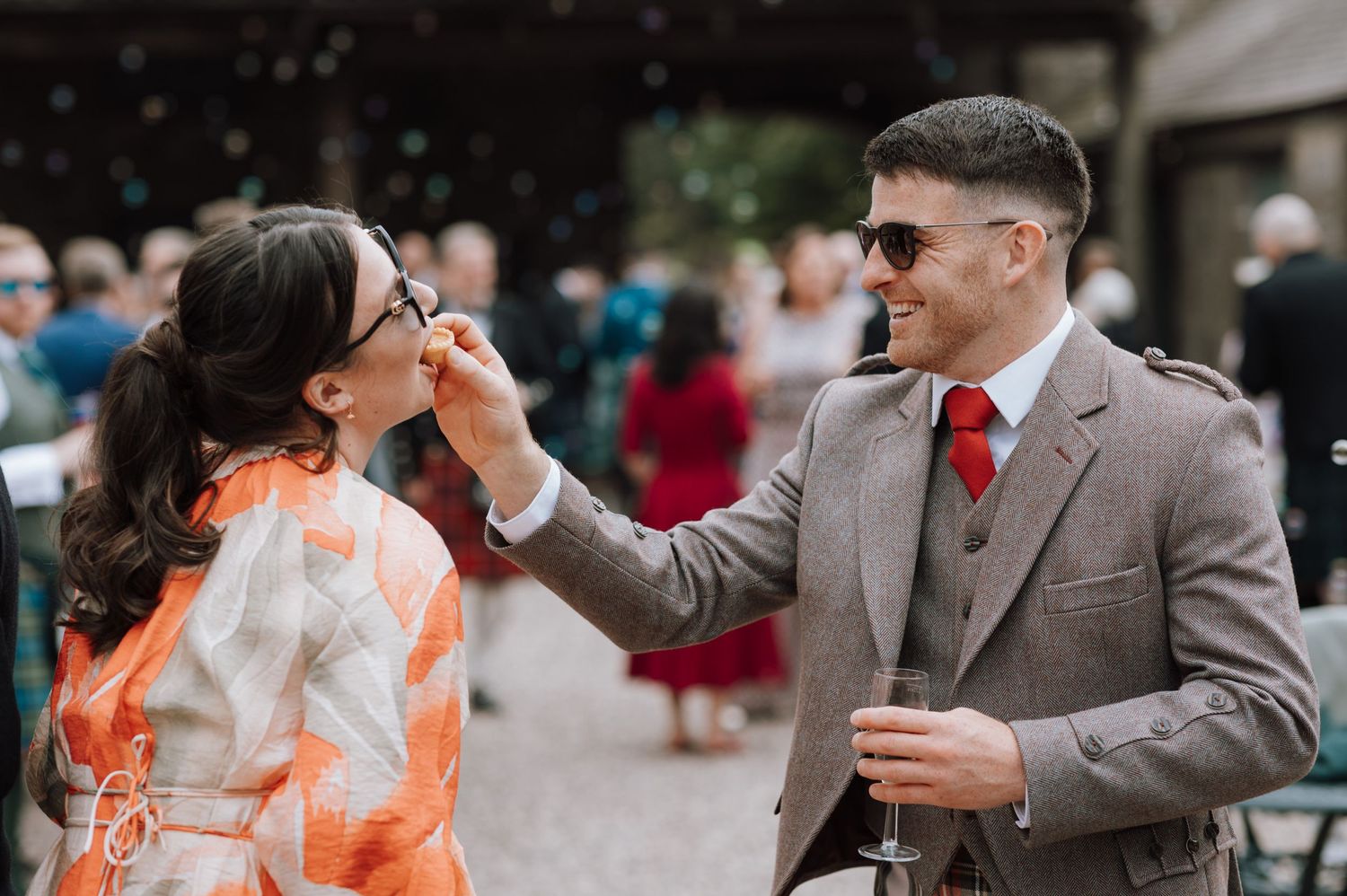 A couple shares a playful moment during their wedding celebration outdoors.