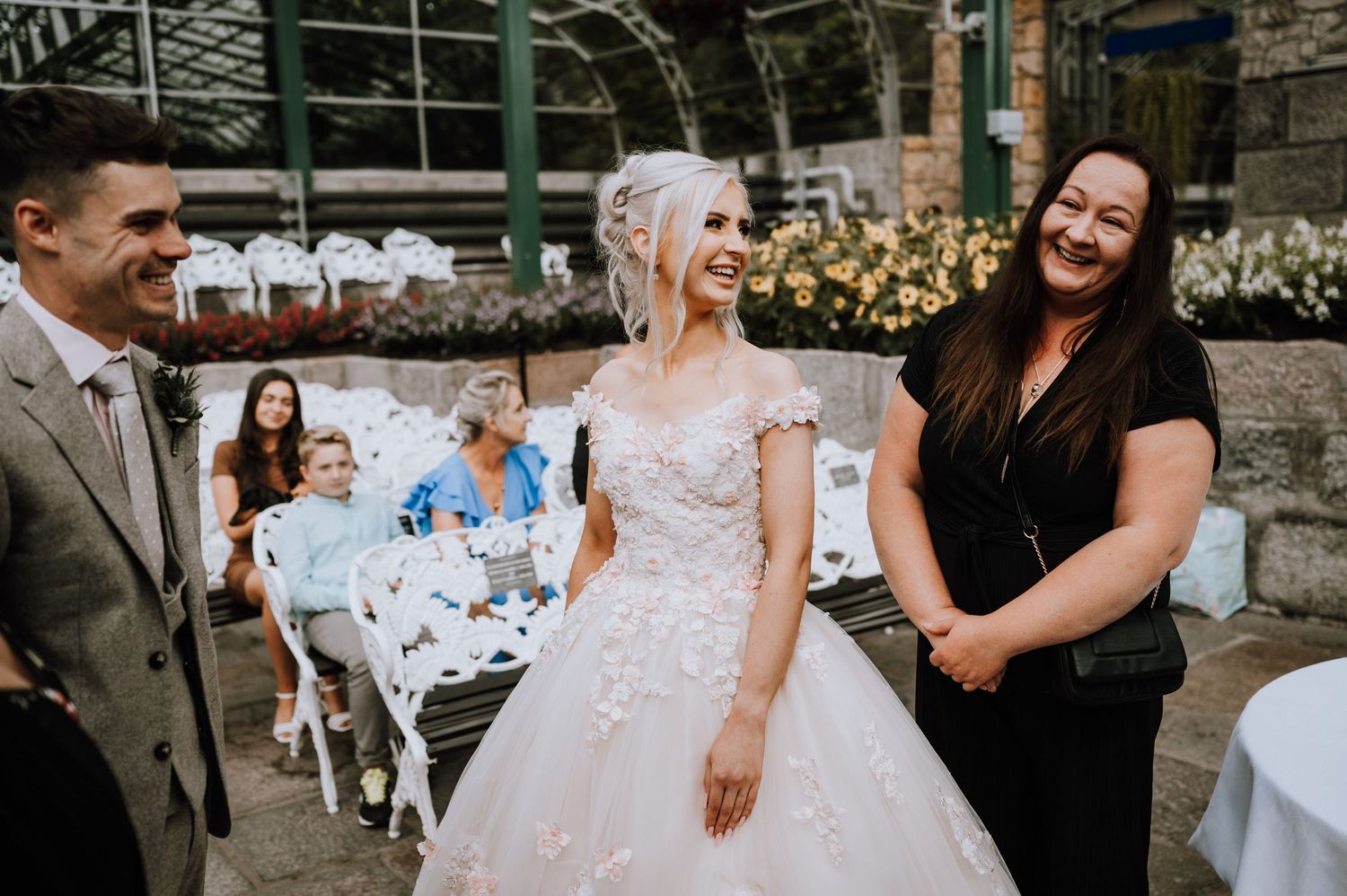 A joyful outdoor wedding ceremony with white chairs and floral decorations in a garden setting.