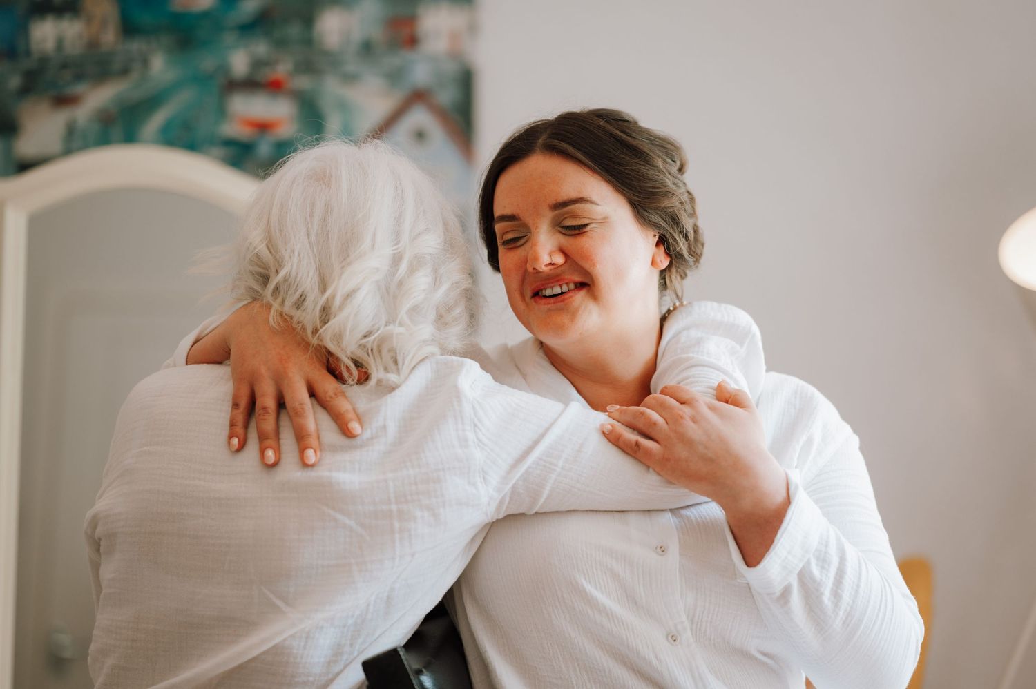 Two people sharing an emotional embrace while wearing white robes.