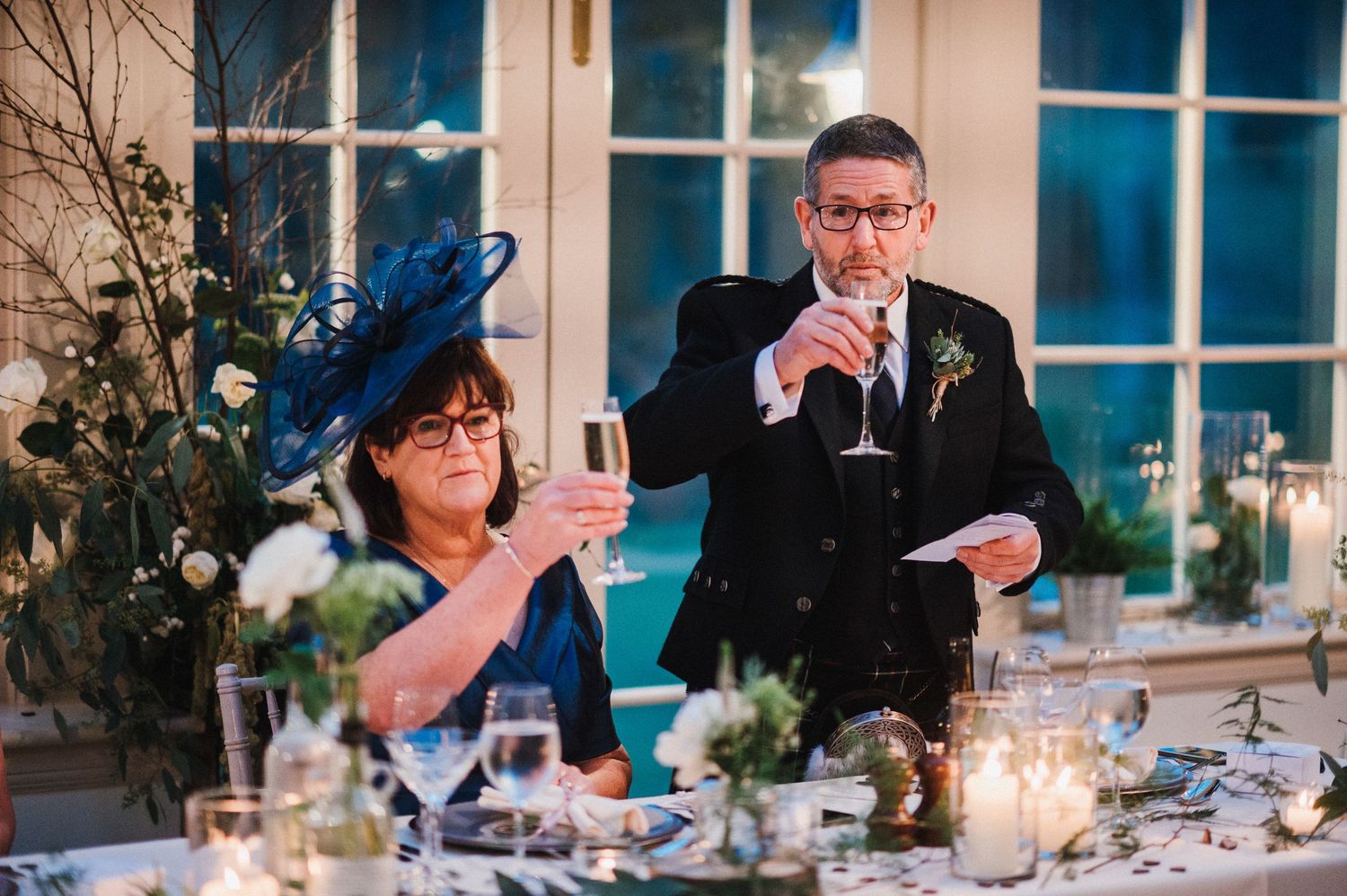 Wedding reception celebration with formal dining setup and window backdrop.