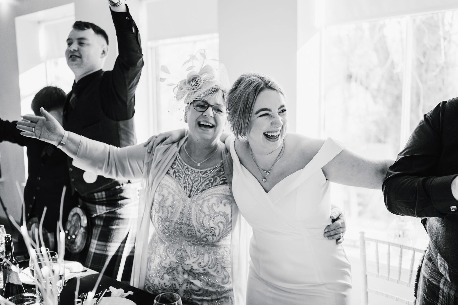 Logie House Wedding Photography. Black and white shot of wedding guests celebrating with arms raised in joy.