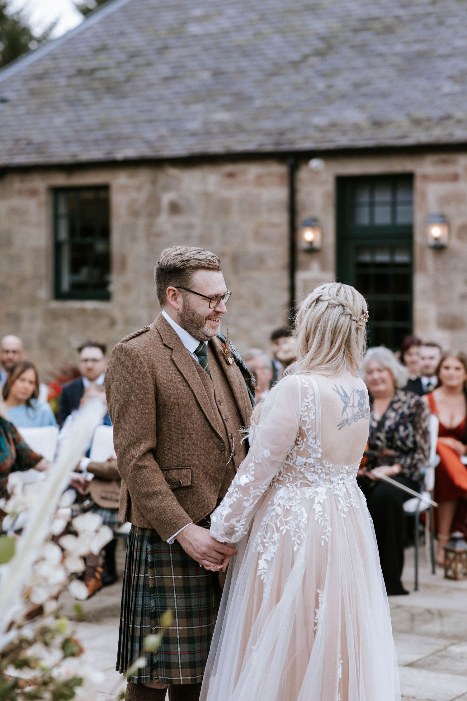 Wedding celebration outside a rustic stone venue with Scottish highland touches.