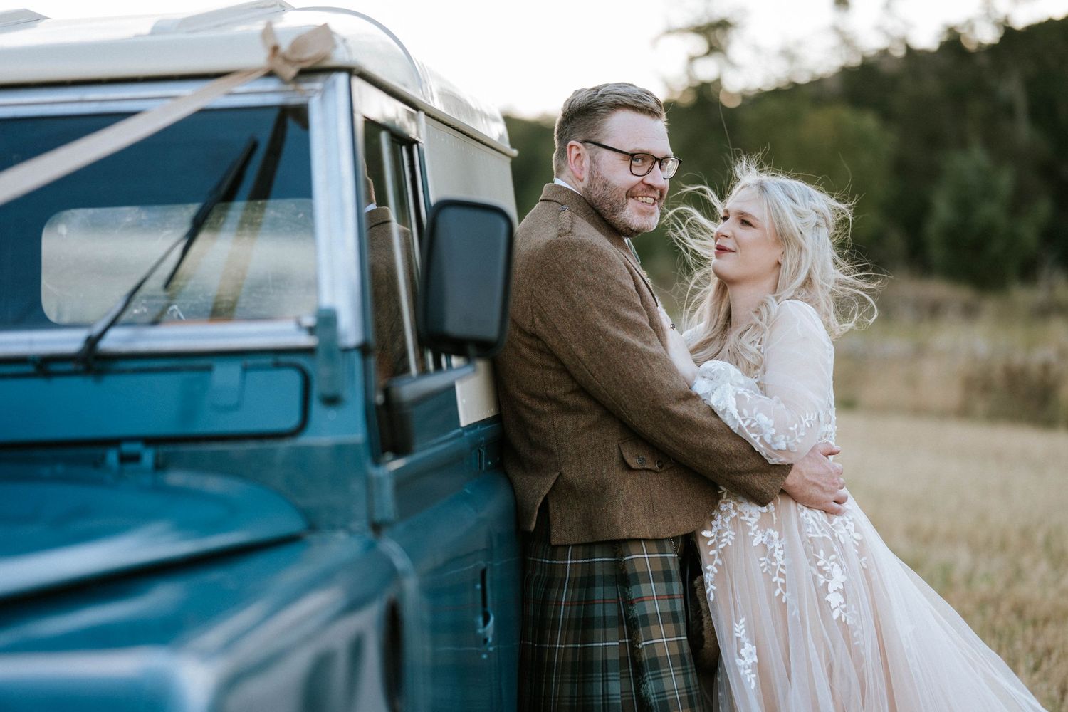 Couple posing beside a vintage blue truck during their wedding photoshoot.