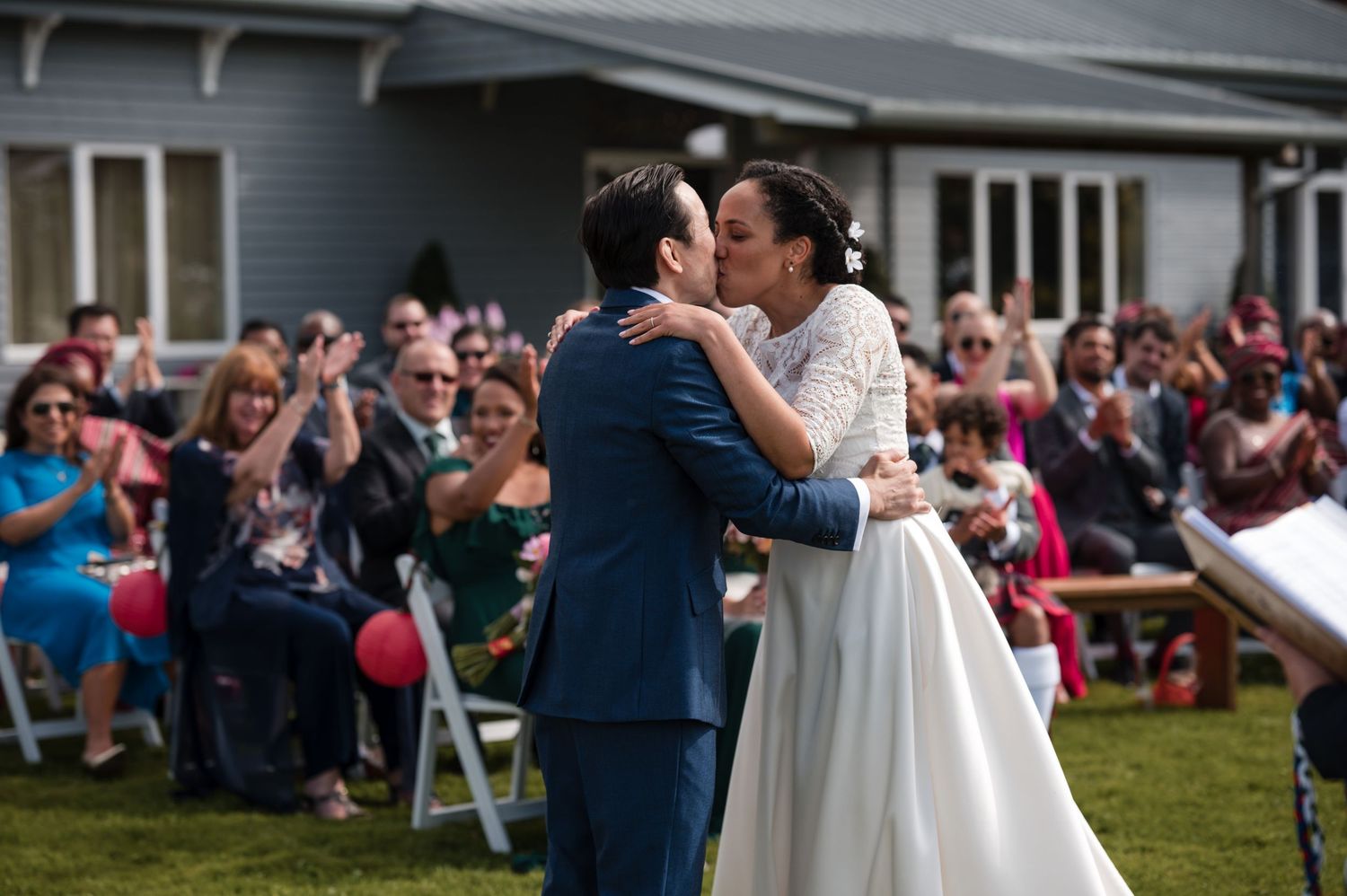 Wedding couple dancing surrounded by guests on an outdoor lawn.