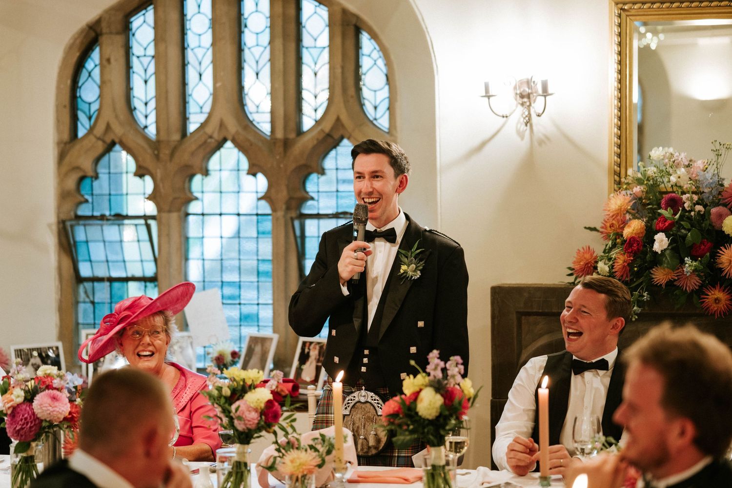 Gothic arched windows and ornate decor frame an elegant wedding reception celebration.