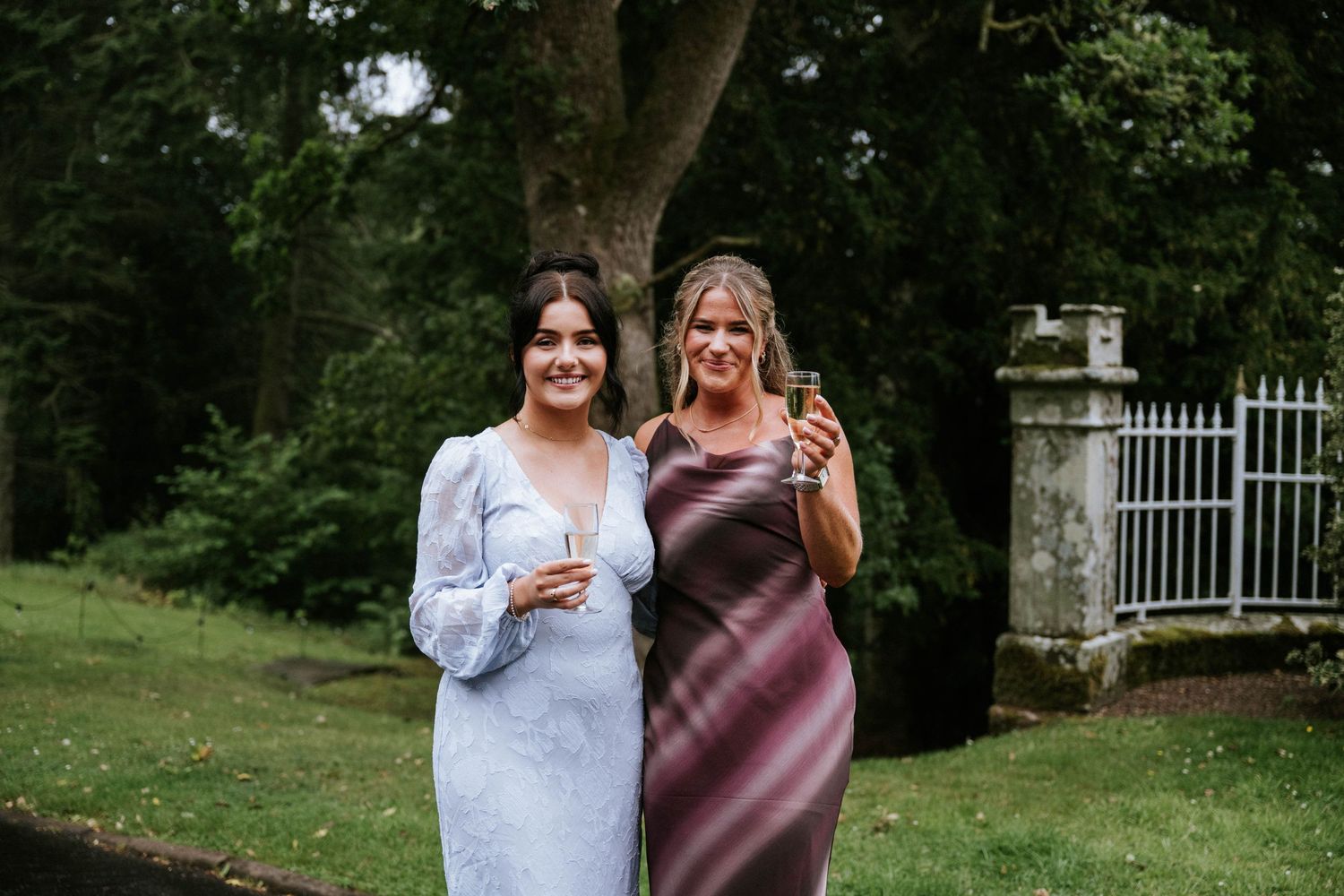 Wedding party members celebrate together outdoors in a garden setting.