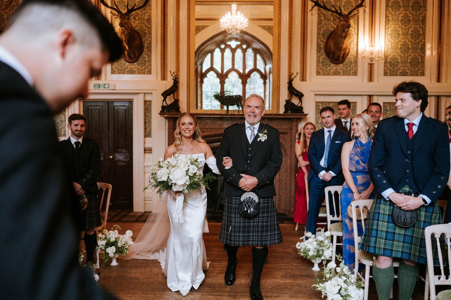Elegant wedding ceremony in a grand ballroom with ornate gold details and chandeliers.