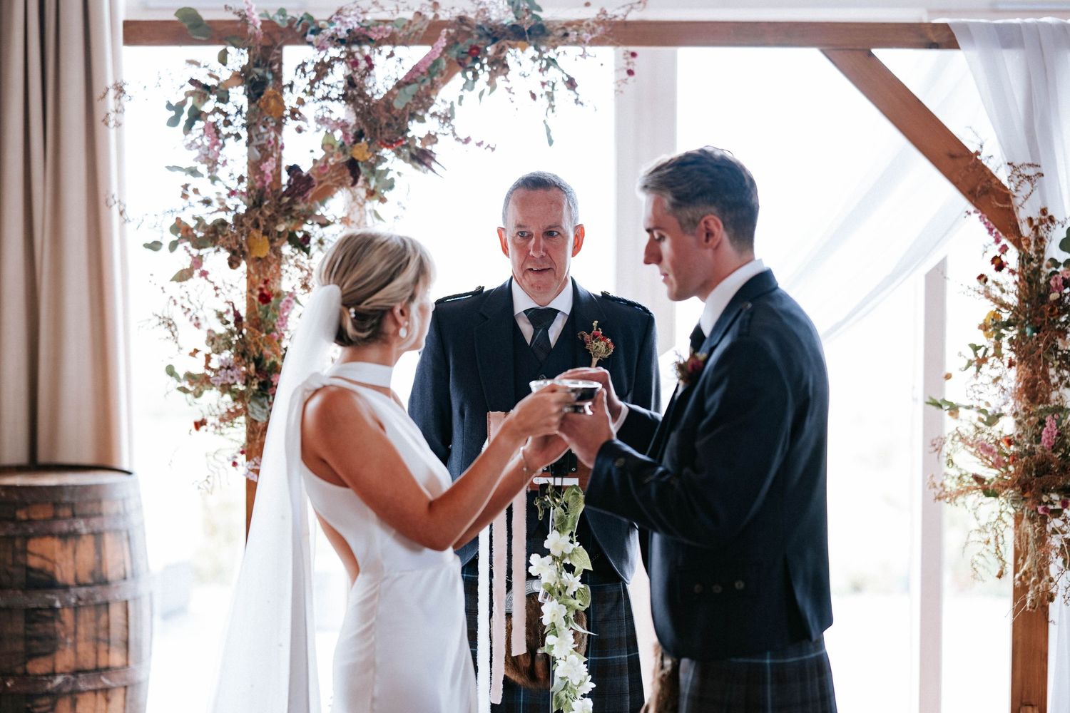 Wedding reception venue decorated with rustic wooden beams and autumn floral arrangements.