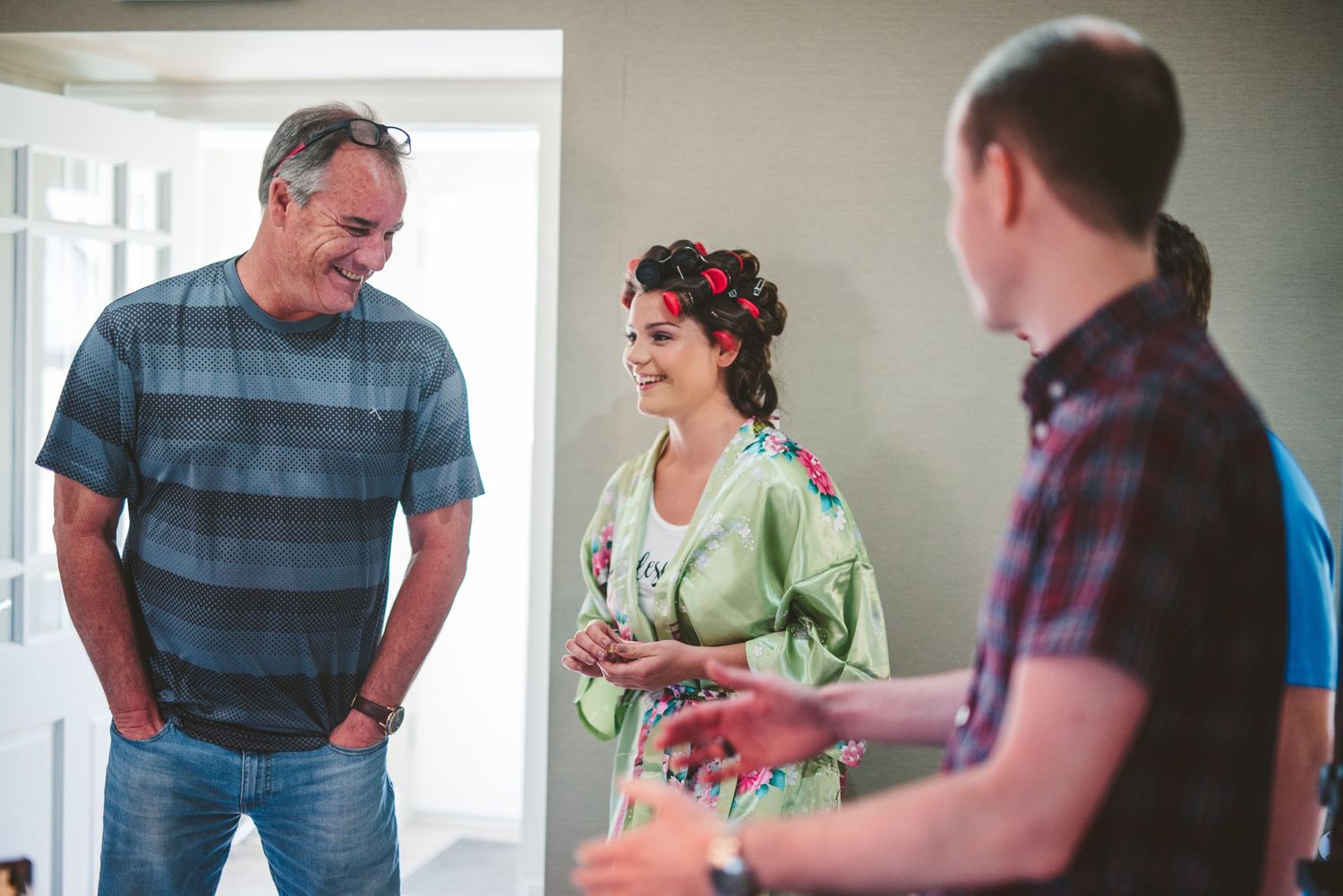 Three people having a casual conversation in a bright interior room.