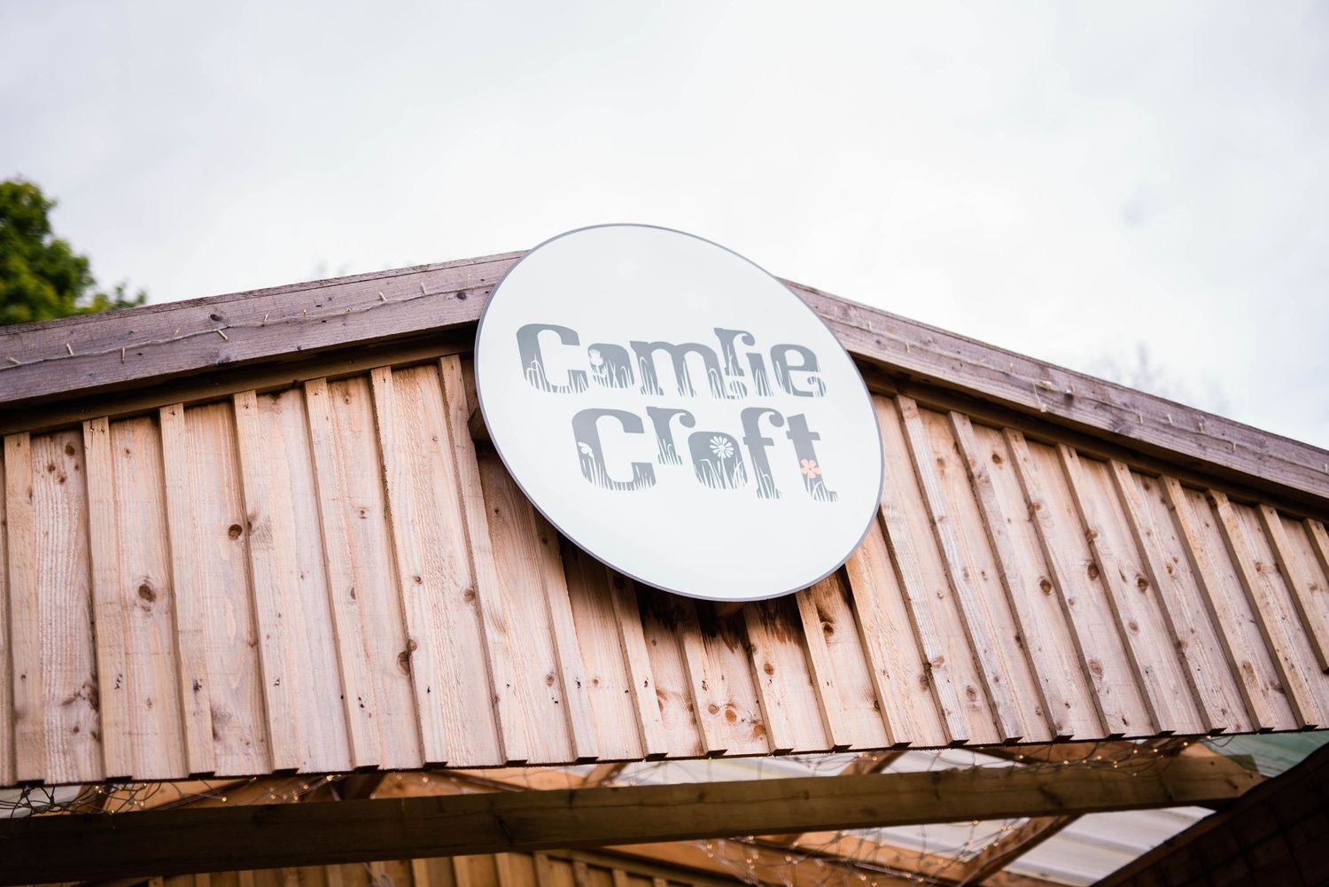 Wooden building exterior with a circular 'Cambie Creek' sign mounted on vertical siding.