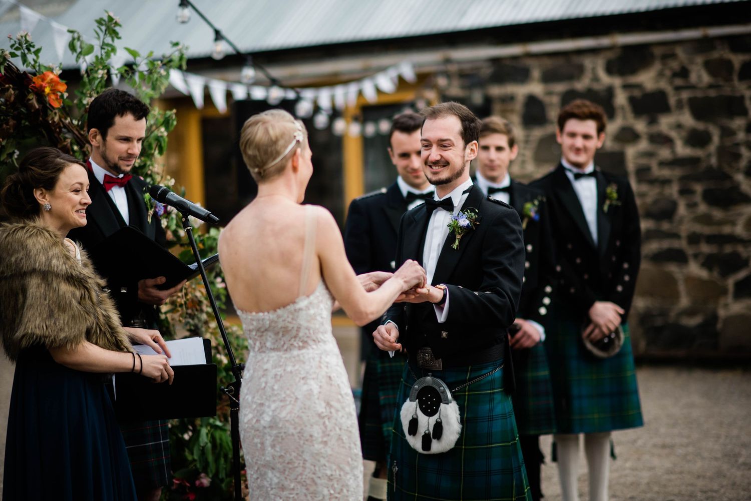 A wedding ceremony moment between the couple and wedding party in traditional Scottish attire.