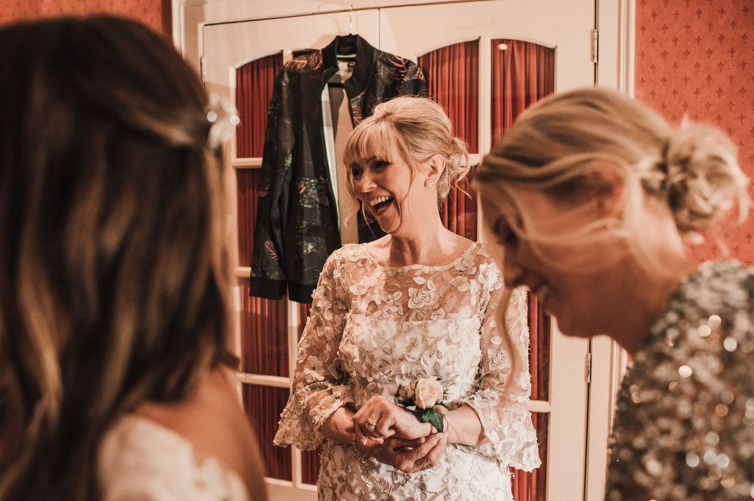 Elegant wedding preparations showing a lace and beaded dress being fitted in a warmly lit room.