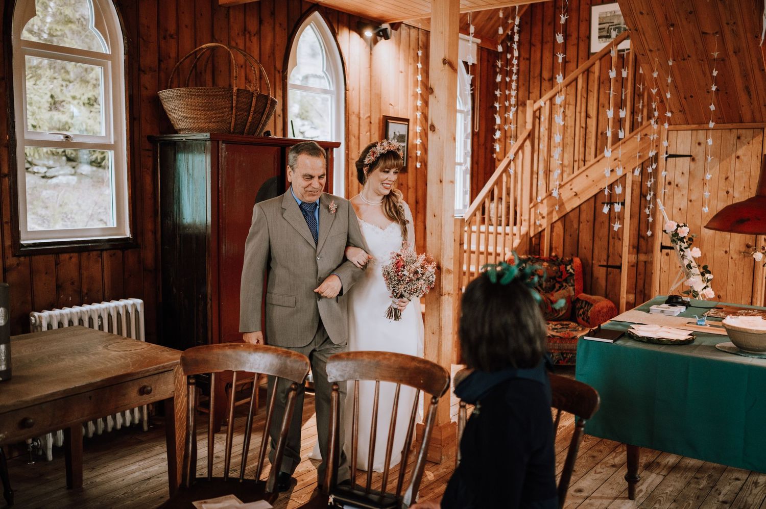 A wedding ceremony in a rustic venue with wood paneling and decorative string lights.
