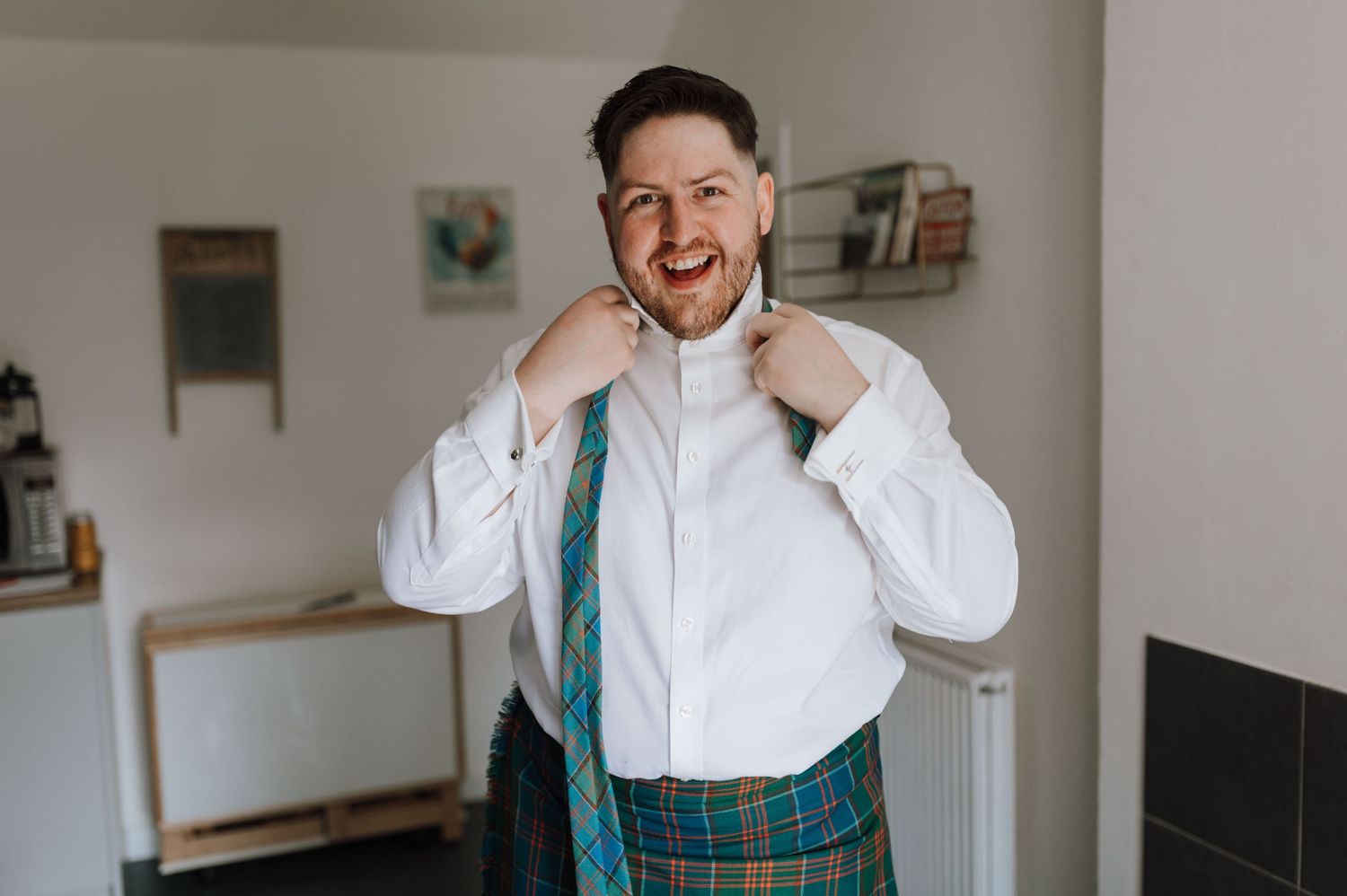 Person in traditional Scottish attire adjusting formal white collar.