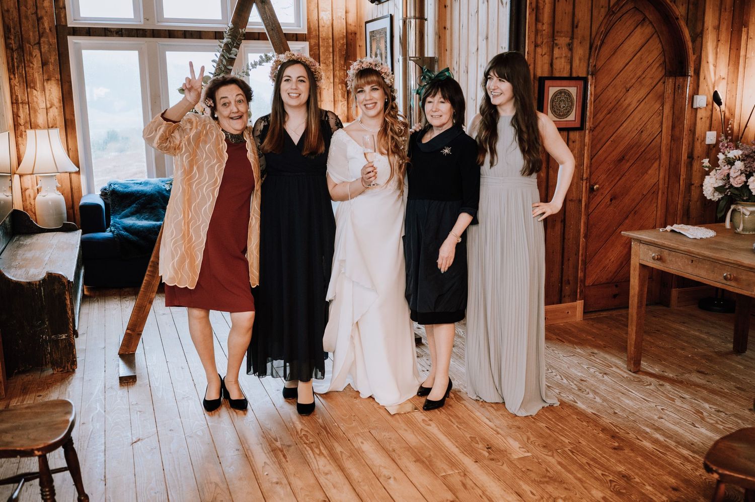 Wedding party poses together on hardwood floors in a rustic indoor venue.