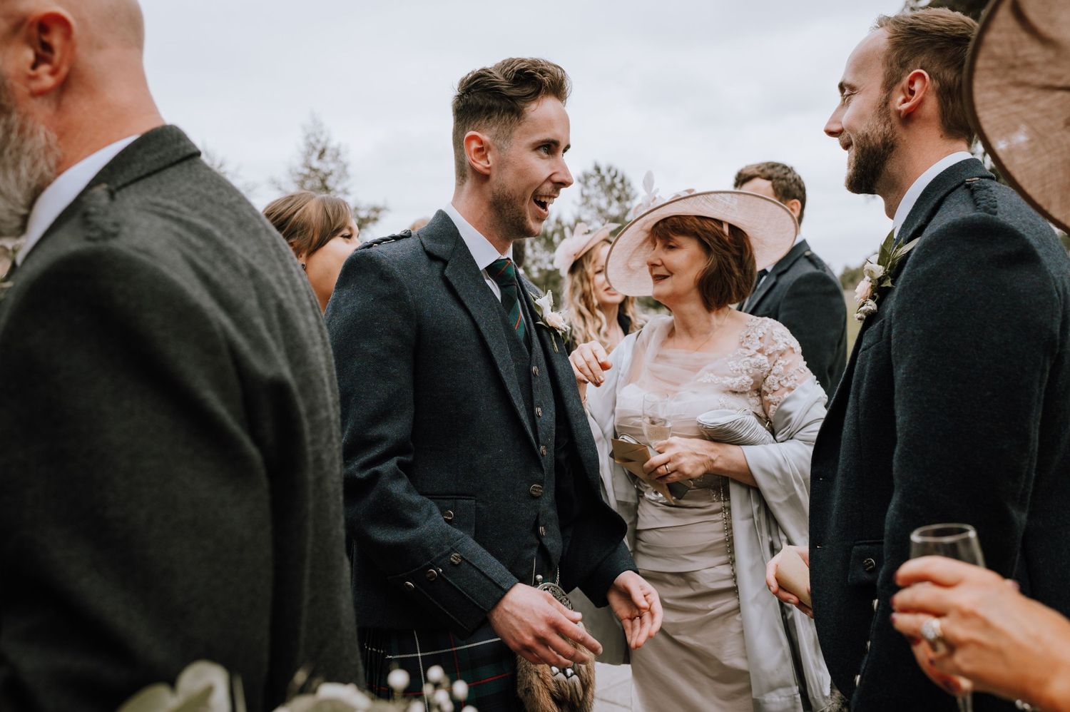 Wedding guests chatting and laughing during an outdoor reception.