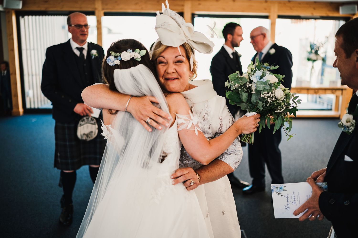 Two wedding attendees share an emotional embrace during a Scottish themed celebration.