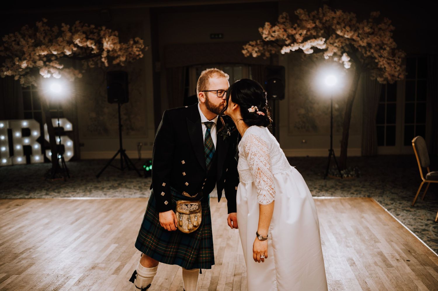 Scottish-Japanese fusion wedding celebration with couple dancing on wooden floor.