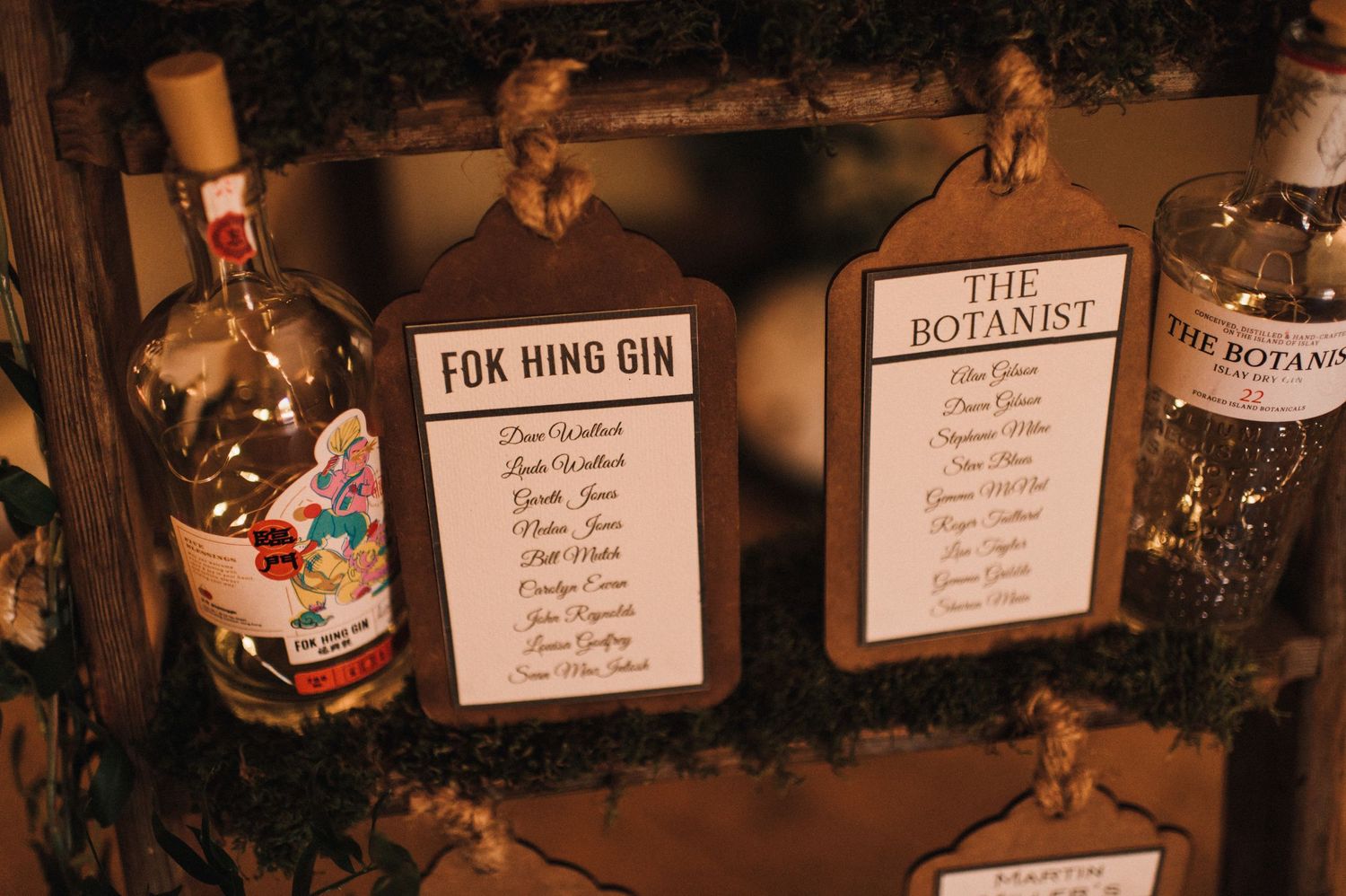 Wedding seating chart displays with gin bottle decor and name lists.