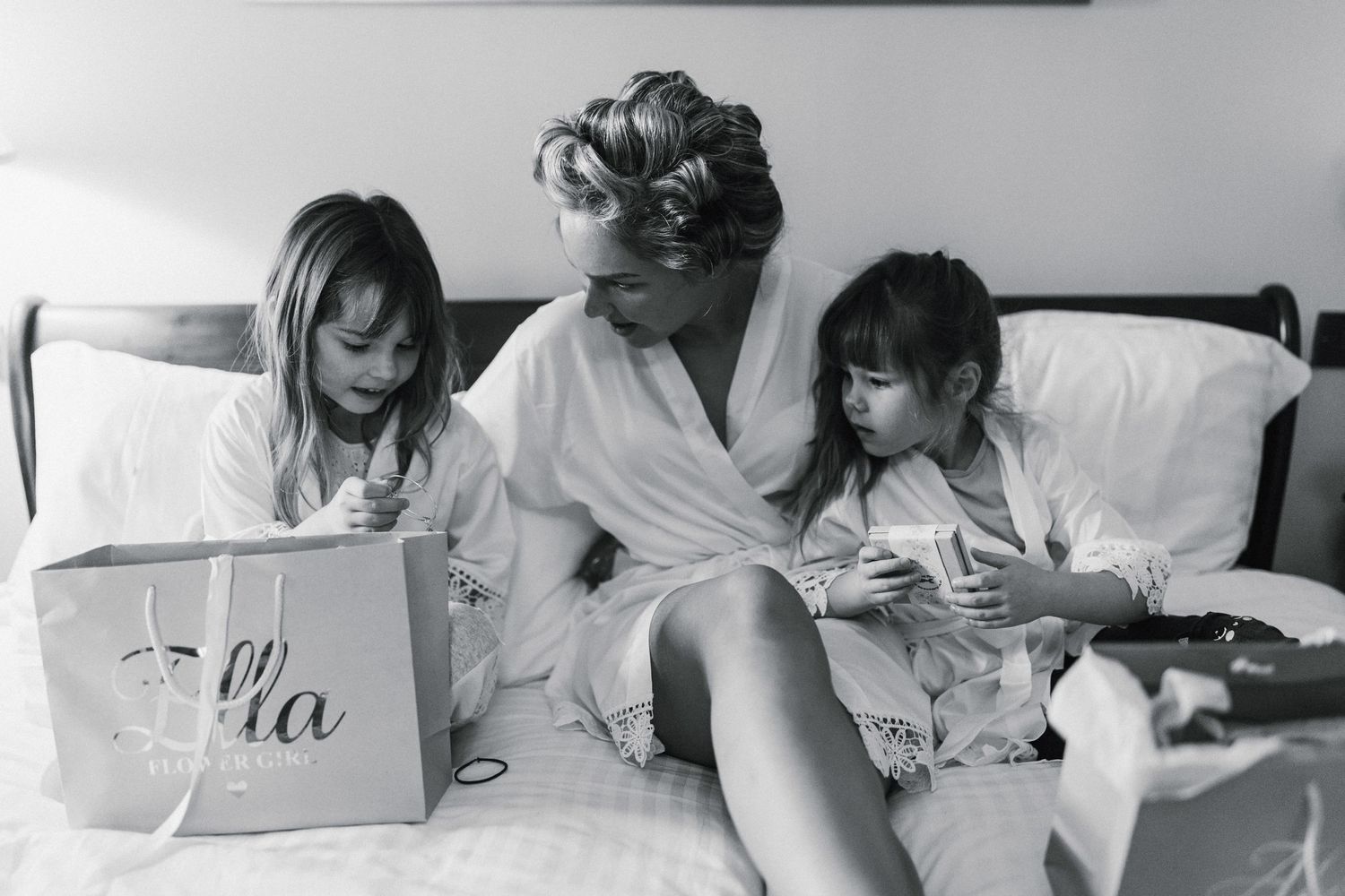 Black and white image of people reading together on a bed.