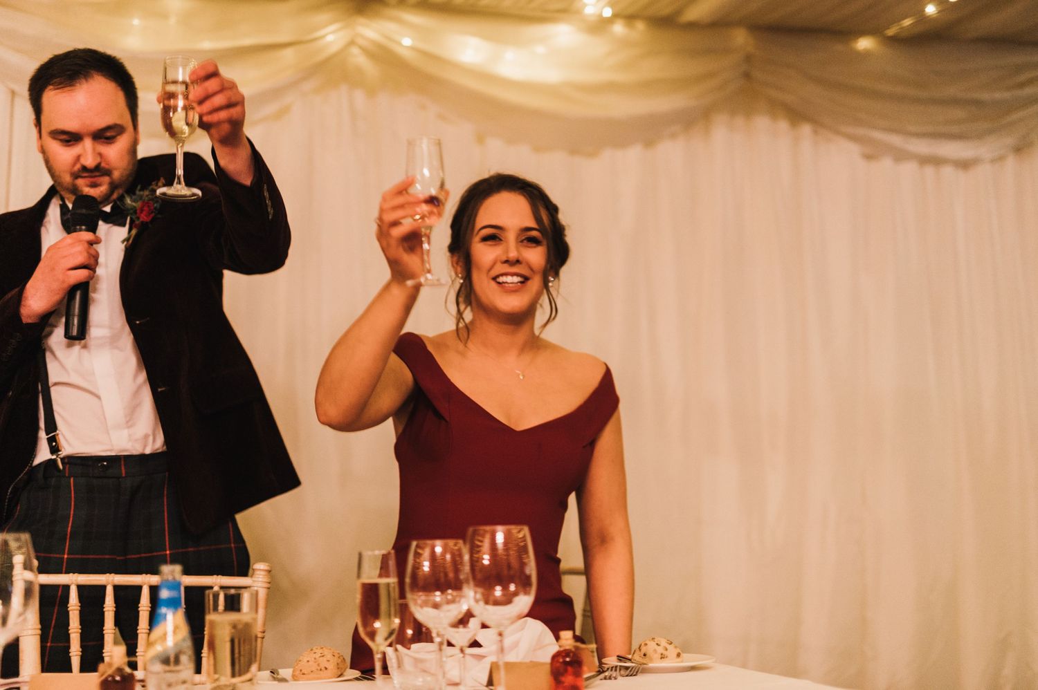 A couple raises their glasses in a toast during wedding reception celebrations.