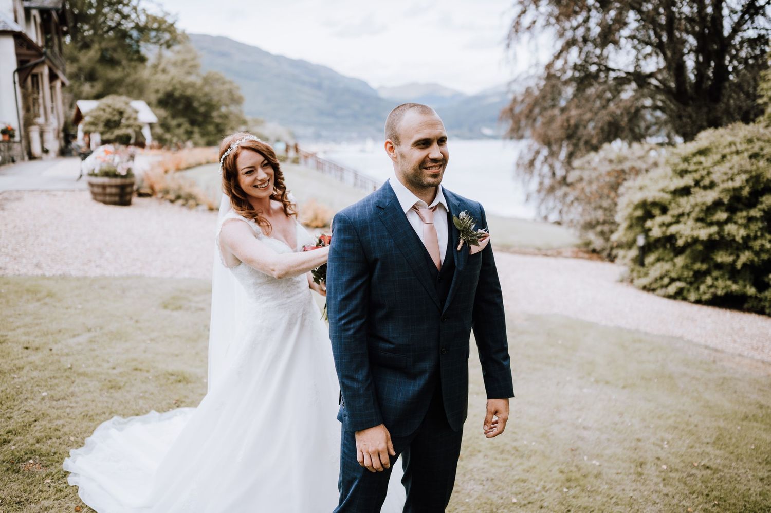 Wedding couple walking outdoors with lake and mountains in background.