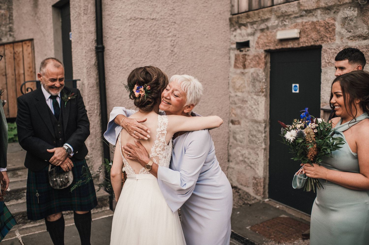 Emotional wedding greetings outside a rustic stone building in Scotland.