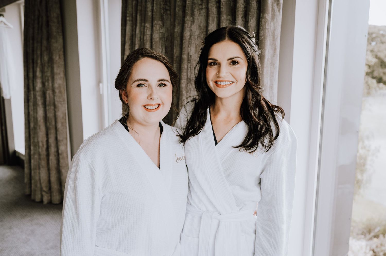 Wedding party members in white robes posing together indoors. Meldrum House Wedding Photography.