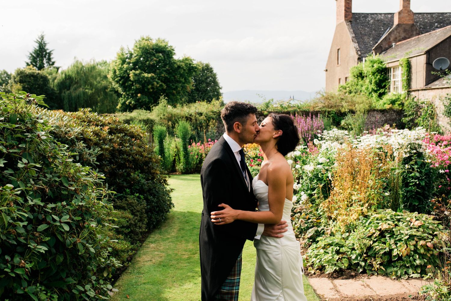 A romantic moment shared in a lush garden with blooming flowers and greenery.