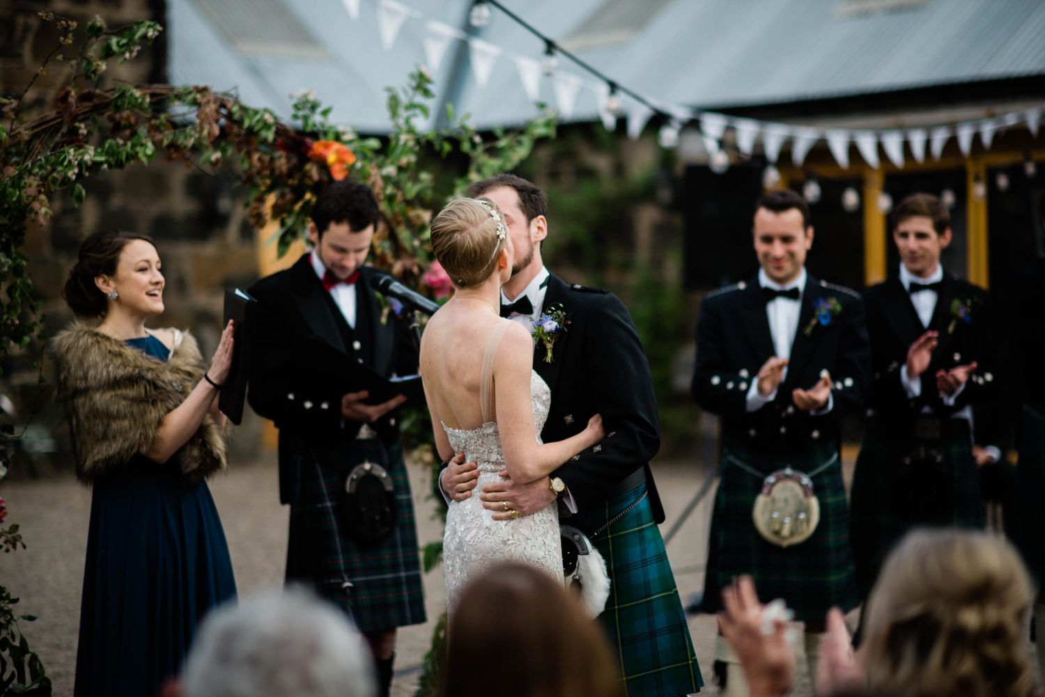 A celebratory moment during a Scottish-themed outdoor wedding ceremony.