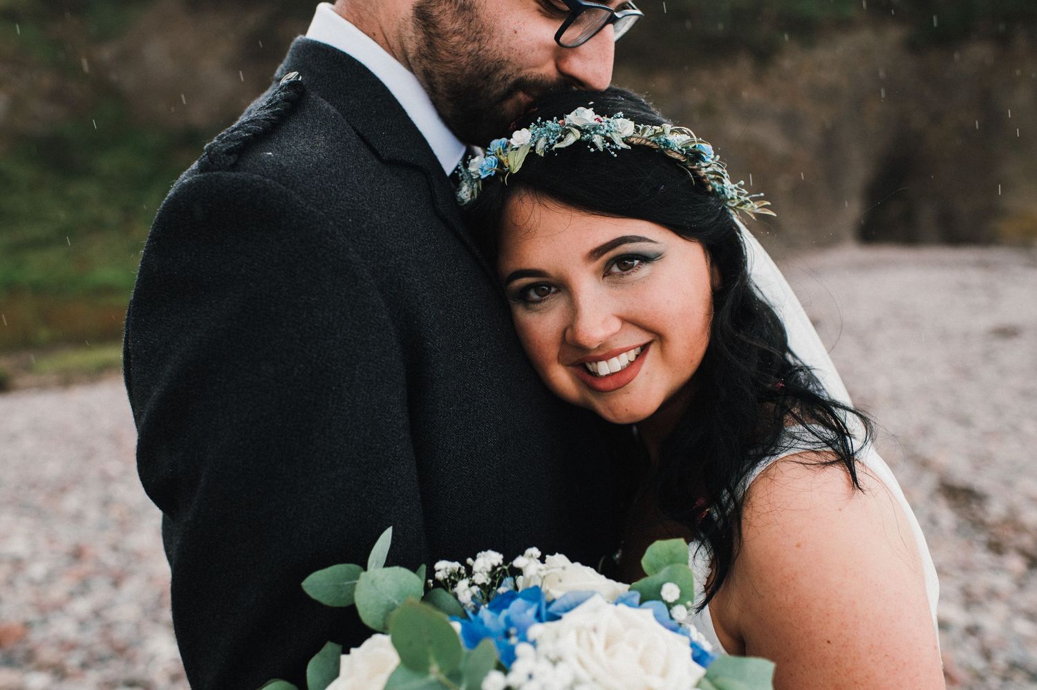 Close-up wedding portrait with blue flowers and greenery bouquet.