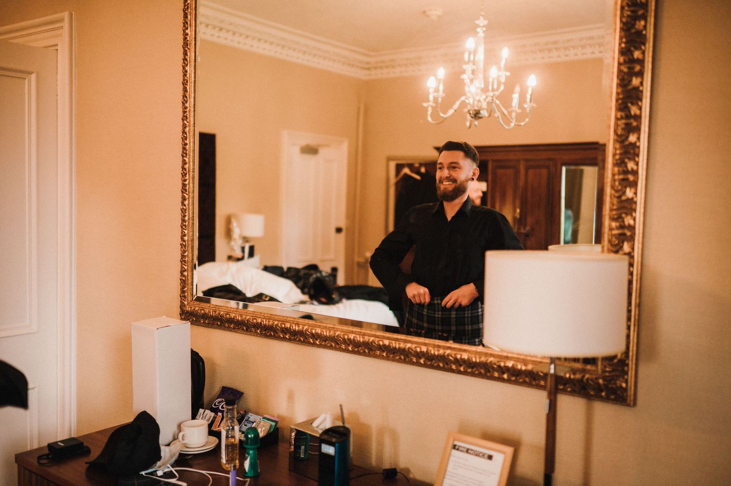 A reflection in an ornate gold mirror captures preparation moments before a formal event.