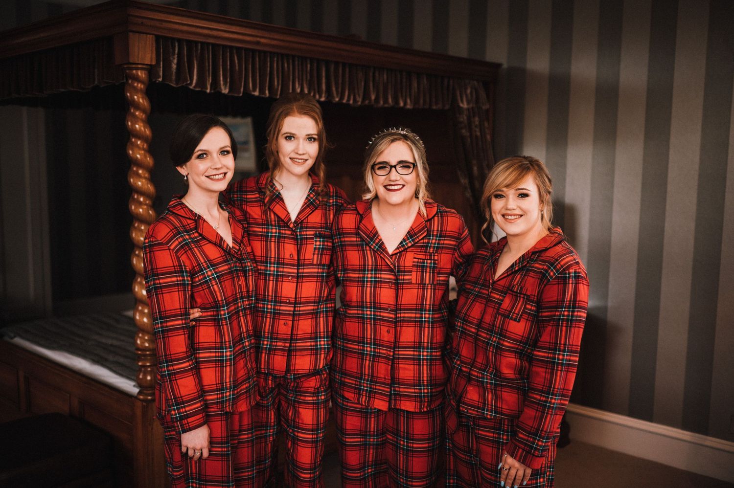 Four people wearing matching red plaid flannel pajamas standing together in a formal room.