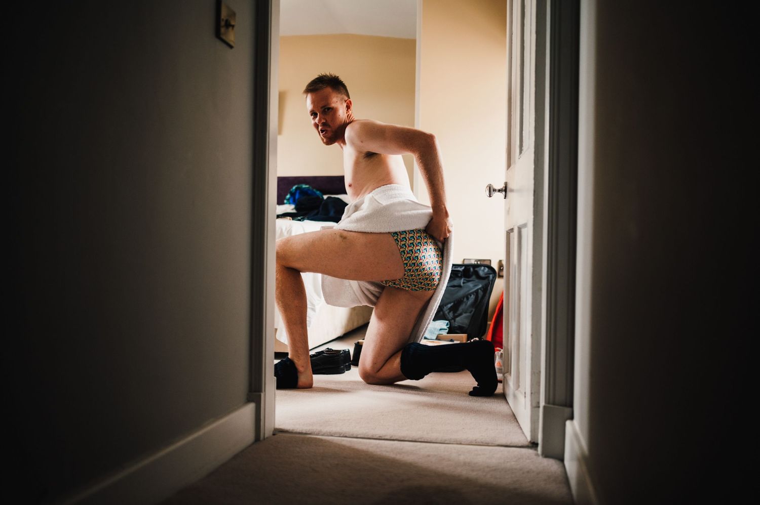 Person getting dressed in bathroom doorway while preparing for formal event.