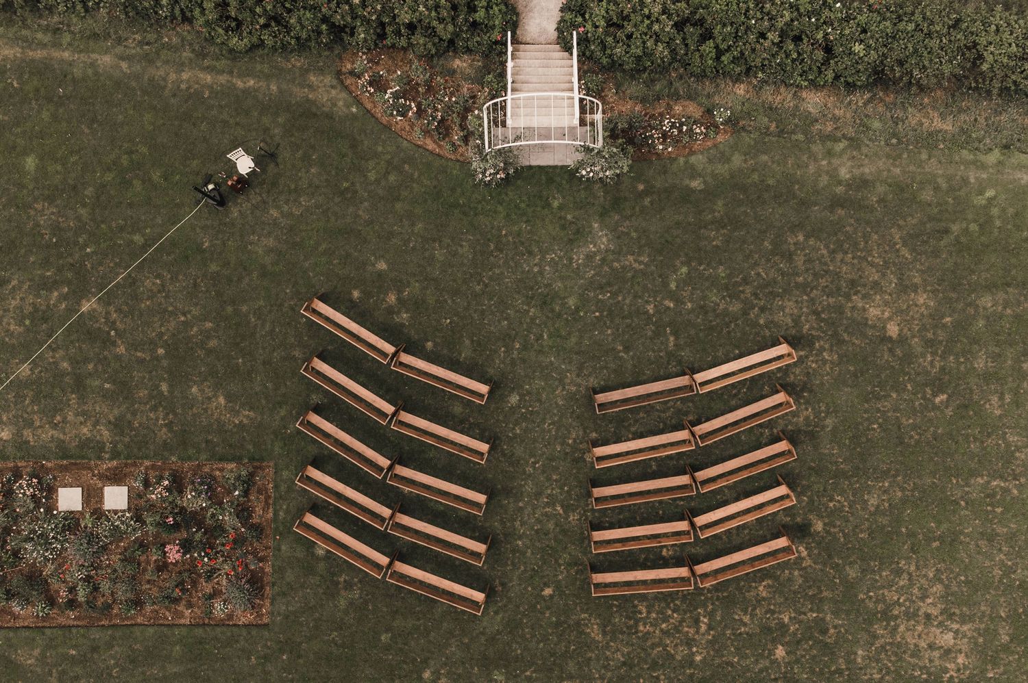 Bird's eye view of wooden benches arranged in two sections on a green lawn for an outdoor ceremony.