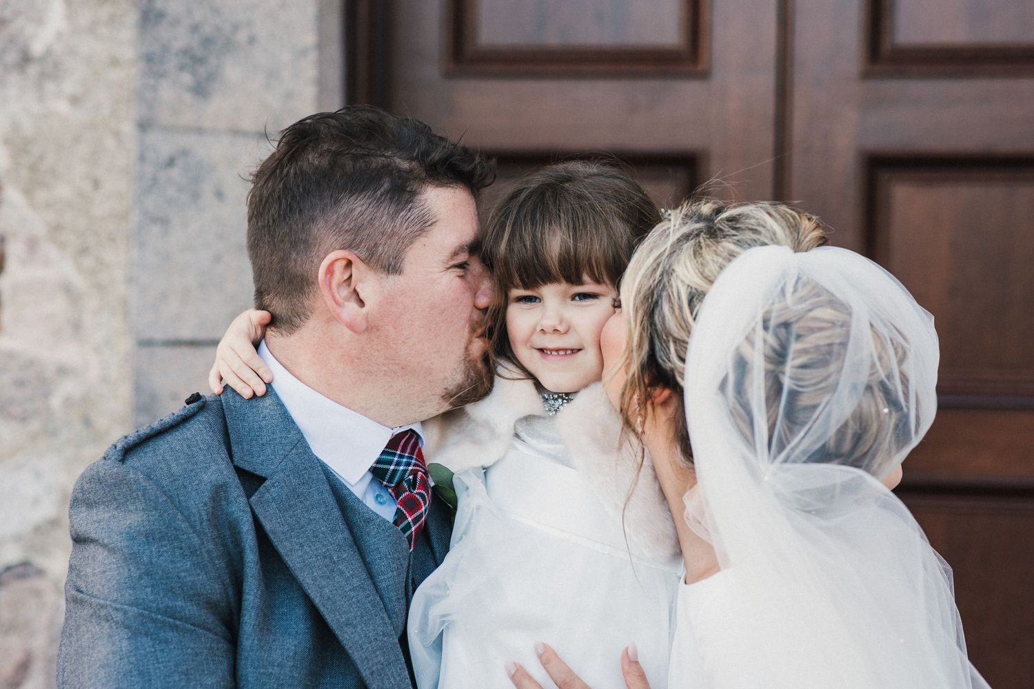 A tender family moment captured between wedding guests outside a church door.