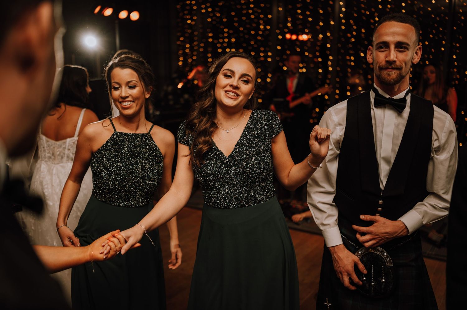 Wedding guests dancing and celebrating at reception with elegant formal attire.