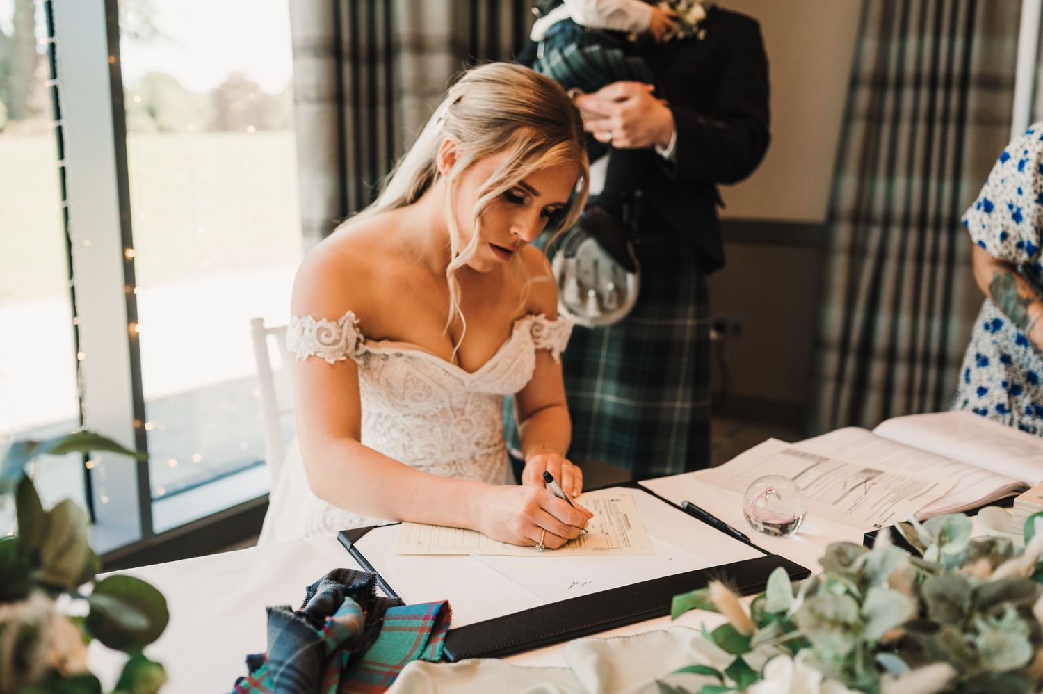 A wedding document signing moment with elegant floral decorations and natural lighting.