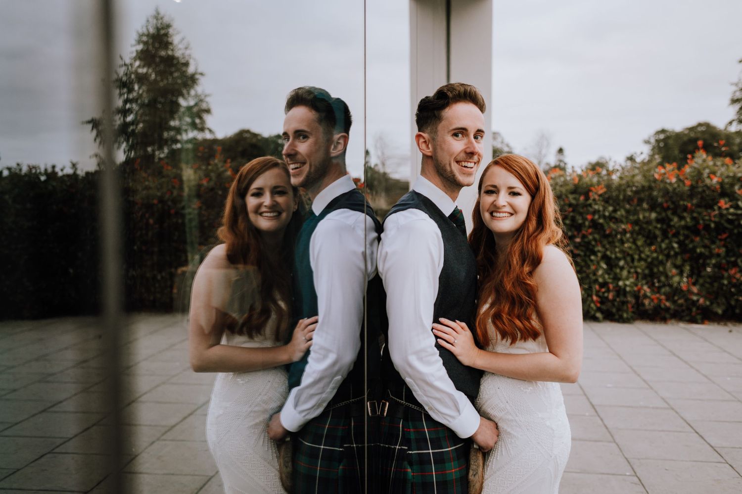 A stylish wedding group creates a fun back-to-back pose on an outdoor patio.